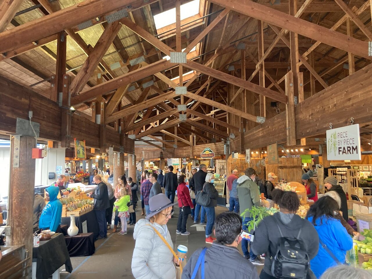 Shoppers walk past covered vendor stalls at the Olympia Farmers Market.